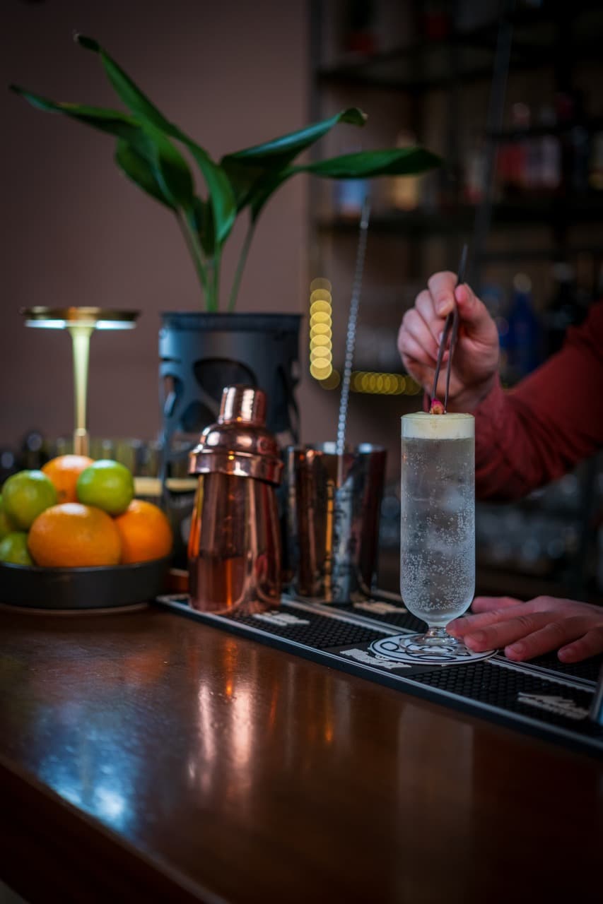Bright fizzy citrus cocktail in a short glass with a decorative garnish, displayed on a polished bar in an upscale St. Julian’s lounge.