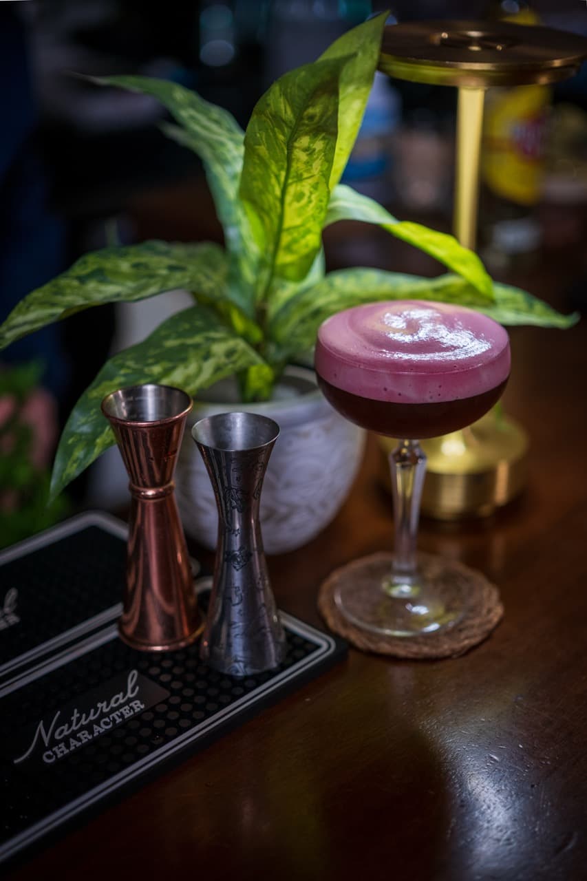 Deep purple cocktail adorned with a delicate flower garnish, highlighting the elegance of St. Julian’s nightlife scene